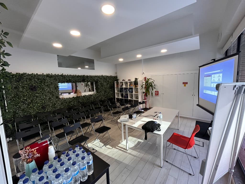 Sala preparada para formação ou evento no Cowork Malvarosa, cadeiras, projector, ecrã e parede verde